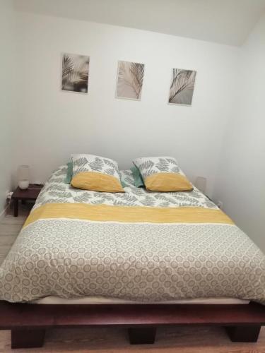 a bed in a bedroom with two pillows on it at Appart'Hôtel Lagnieu in Lagnieu