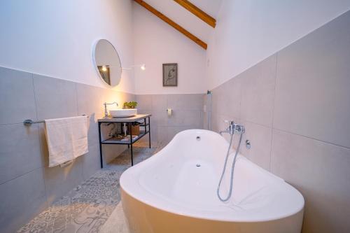 a white bathroom with a tub and a sink at House DIKA- sauna & jacuzzi in Otočac