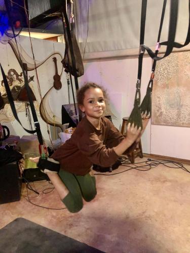 a young boy is sitting on a swing in a room at Good Life Dacha Wellness Homestay in Pai