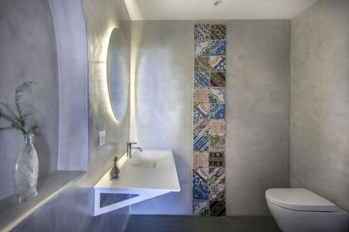 La salle de bains est pourvue d'un lavabo blanc et de toilettes. dans l'établissement Salina Case Vacanza, à Malfa