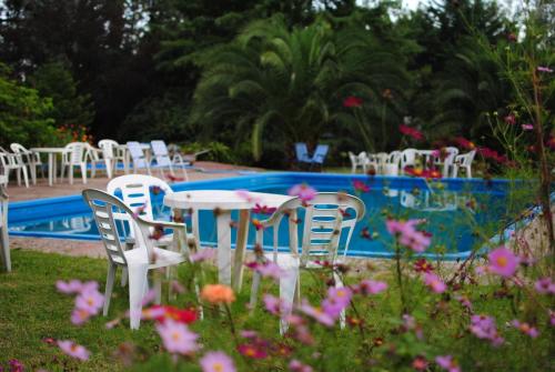 a table and chairs next to a pool with flowers at CABAÑAS LA ARBOLEDA DE TOMASA in Villa Rumipal