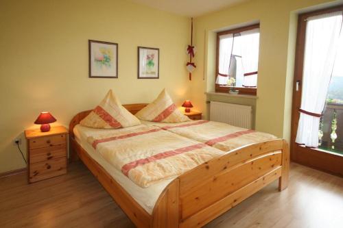 a bedroom with a wooden bed and two windows at FW Zum Königshang in Bodenmais