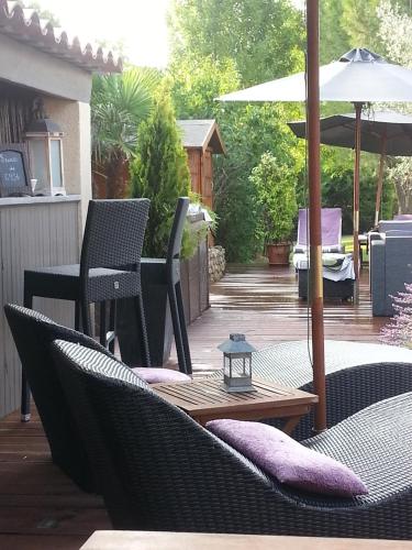 a patio with chairs and a table and an umbrella at Les Chambres d'Hôtes de la Ferrage in La Tour-dʼAigues