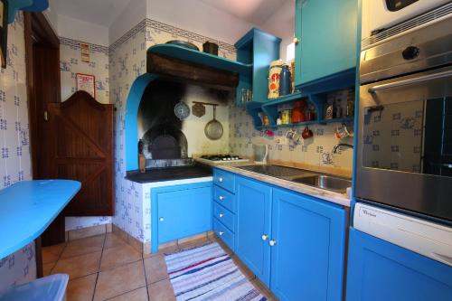 a blue kitchen with blue cabinets and a sink at Casa do Ribeirinho in Porto Moniz