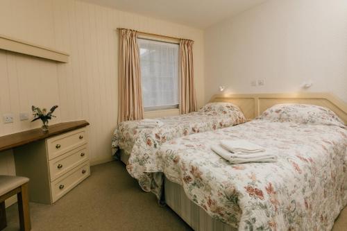 una camera da letto con due letti, un comò e una finestra di Galwad y Mor a St. Davids