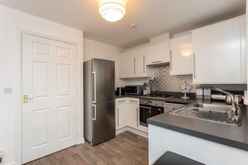 a kitchen with a stainless steel refrigerator and white cabinets at Amazon View in Bowburn