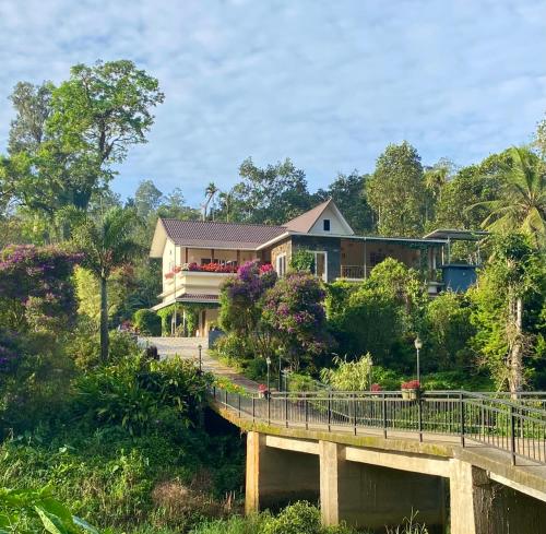 a house on a bridge over a river at Flower Valley Plantation Homestay in Munnar