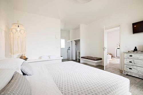 a white bedroom with a white bed and a dresser at Santa Maria Village Resort & Spa in Adamas