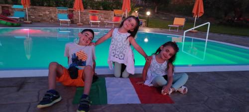 a group of three girls sitting next to a swimming pool at Agri Resort Masusa in Aquara