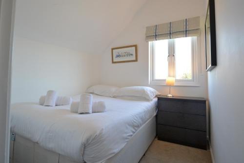 a bedroom with a white bed and a window at Lapwing Lake Lodge in Cirencester