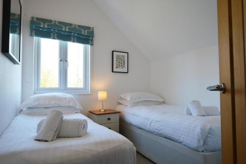 two twin beds in a room with a window at Lapwing Lake Lodge in Cirencester