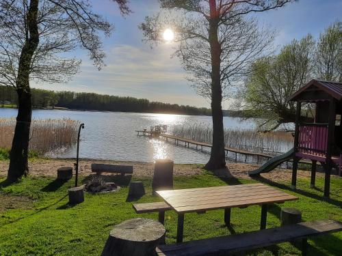 a park with a bench and a playground next to a lake at Domek Letniskowy w Tumianach in Tumiany