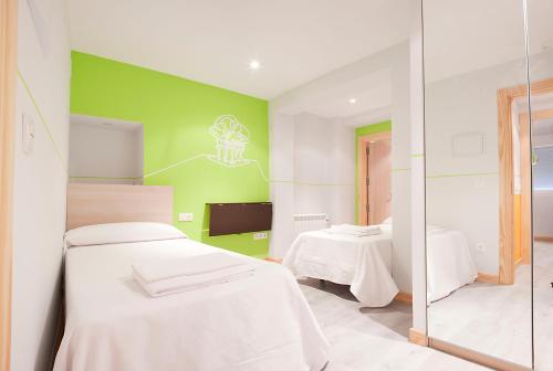 a room with two beds and a green wall at Pensión Herradores in Soria