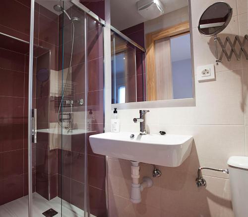 a bathroom with a sink and a shower and a mirror at Pensión Herradores in Soria