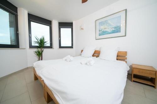 a bedroom with a large white bed with windows at Rheinblick Penthouse Wolke 7 - Neuss/Düsseldorf in Neuss