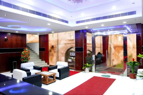 a lobby with white chairs and a red carpet at Hotel Hiton in Perintalmanna