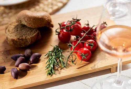 a wooden cutting board with bread and tomatoes and a glass of wine at Santa Maria Village Resort & Spa in Adamas