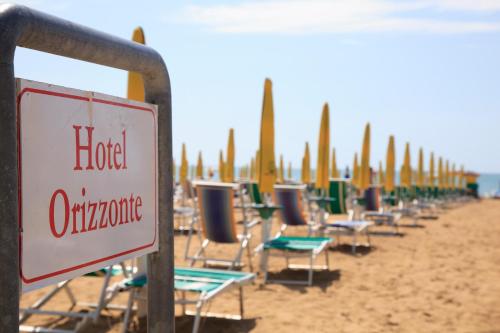 a row of lounge chairs on a beach at Hotel Orizzonte in Lido di Jesolo