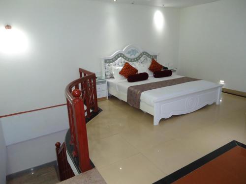 a bedroom with a white bed and a staircase at Hotel Hiton in Perintalmanna