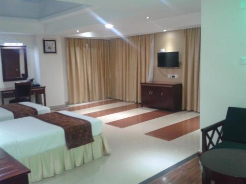 a hotel room with two beds and a flat screen tv at Hotel Hiton in Perintalmanna