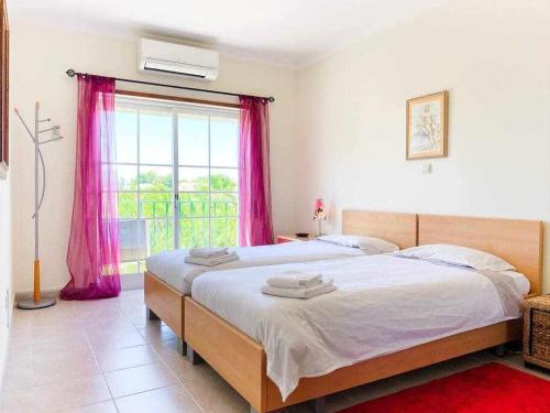 um quarto com 2 camas e uma janela com cortinas cor-de-rosa em DArens Apartment em Alvor