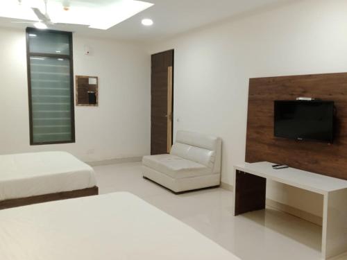 um quarto com uma cama e uma cadeira e uma televisão em HOTEL GOLDEN LEAF em Mohali
