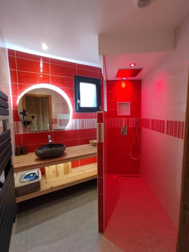 ein rotes Badezimmer mit einem Waschbecken und einem Spiegel in der Unterkunft Nature Cottage Vosges in Anould
