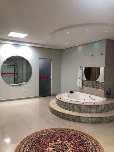 a large bathroom with a tub and a large mirror at Hotel Baeza in Goiatuba
