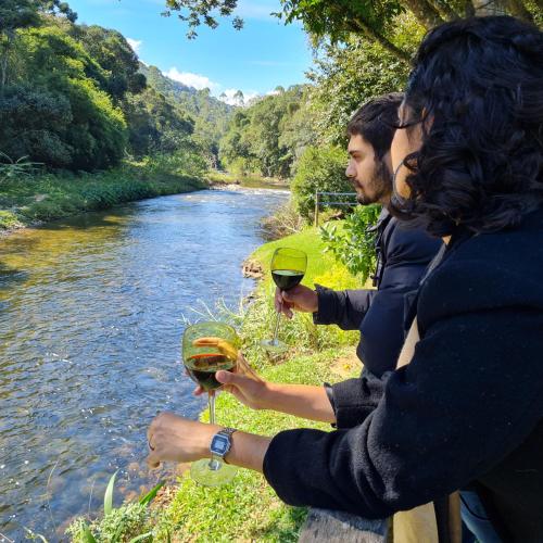 a group of people holding glasses of wine by a river at Pousada Remanso do Rio Preto in Visconde De Maua