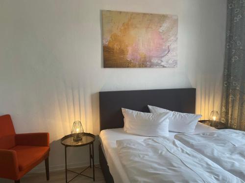 a bedroom with a bed and a chair and a painting at Harzhotel Warnstedter Krug in Thale