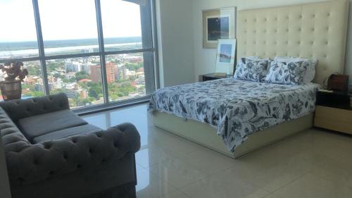 a bedroom with a bed and a chair and windows at Hermoso apartamento en la Arenosa in Barranquilla