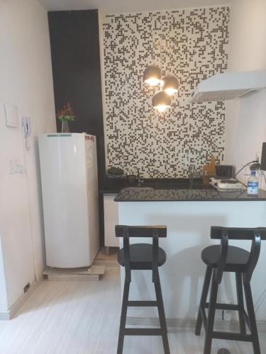 a kitchen with a white refrigerator and two stools at Studio Leblon in Rio de Janeiro