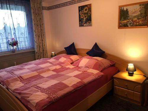 a bedroom with a bed with a plaid blanket and a window at Ferienappartement Peters in Glücksburg