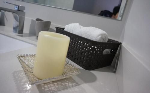a candle on a bathroom counter with a basket of towels at Amazing views SJO, Cozy, Equipped. 24/7 Concierge in San José