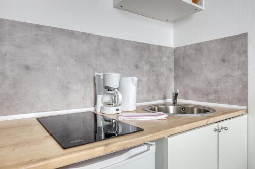 - une cuisine avec un évier et une cafetière sur un comptoir dans l'établissement Le Moulin Haut, à Magny-le-Hongre