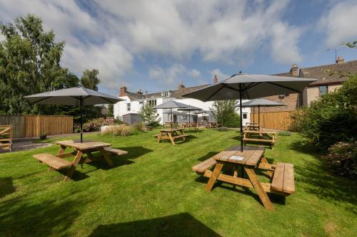 un grupo de mesas de picnic y sombrillas en un patio en The Smiddy Haugh, en Auchterarder