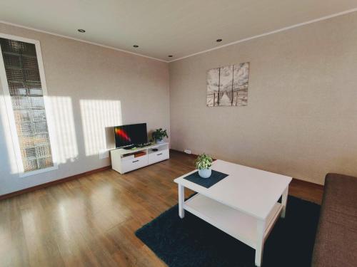 a living room with a white table and a tv at Kotkapesa Apartment in Kiviõli