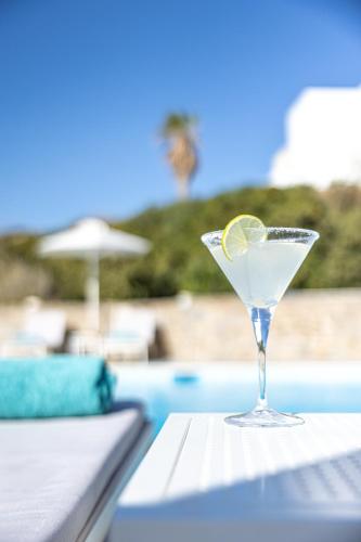 a martini glass with a lemon on a table next to a pool at Akrotiri Hotel in Parikia