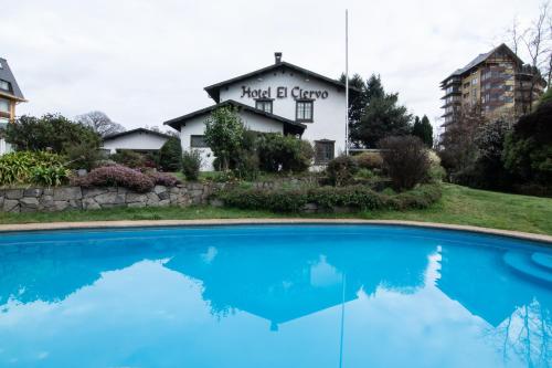 a house with a blue pool in front of it at Hotel El Ciervo in Villarrica