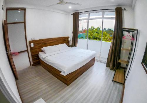 a bedroom with a bed and a large window at Akiri Surf Residence in Thulusdhoo