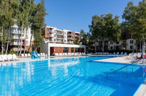 a large swimming pool with chairs and buildings at Aparts Care Balic Polanki in Kołobrzeg