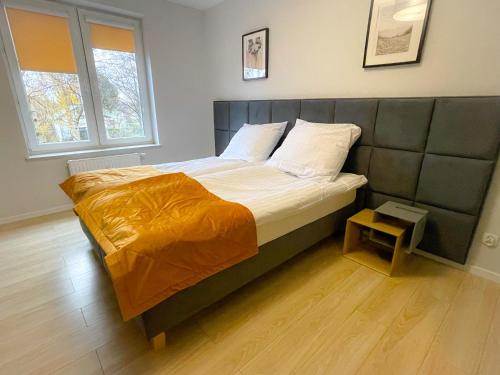 a bedroom with a large bed with an orange blanket at Aparts Care Balic Polanki in Kołobrzeg