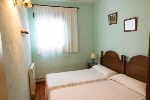 two beds in a small room with a window at Apartamentos Rurales Mayorazgo in Cañete