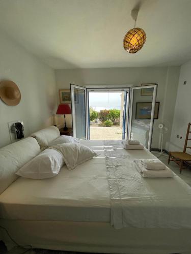 a large white bed in a room with a window at Cape Sunset Villa in Makrotándalon