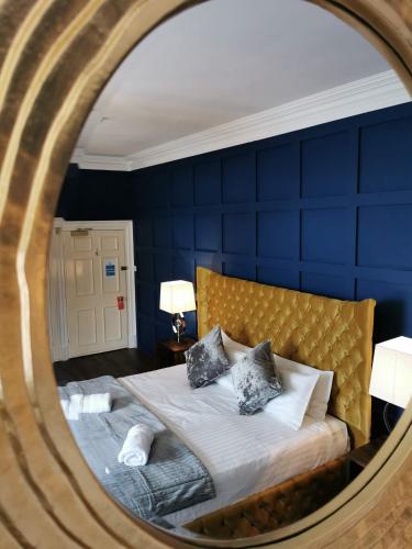 a bedroom with a bed with a blue wall at Manor House Hotel Holy Island in Berwick-Upon-Tweed