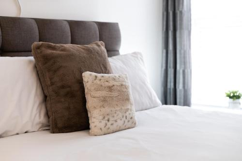 a bed with a pillow and two pillows on it at 3 Baths - Off Road Parking - Garden - 4 Bed Home in Swansea
