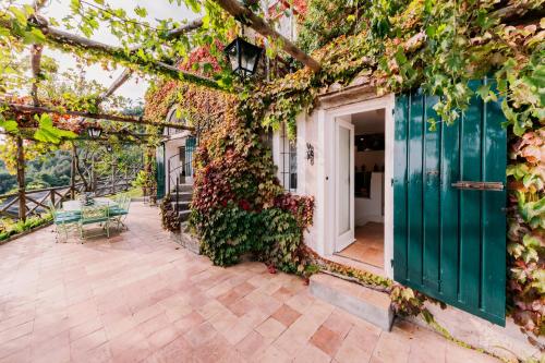 a house covered in ivy with a green door at L'Olearia Luxury Country Villa in Amalfi Coast in Maiori