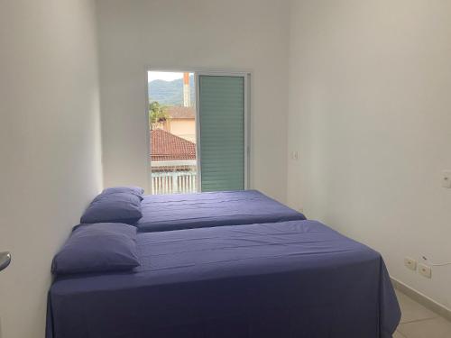 a bed in a white room with a window at Juquehy Casa Confort para Famílias em condomínio in Juquei