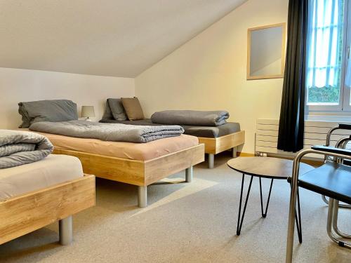 a room with three beds and a table and chairs at VIVA Hostel in Chur