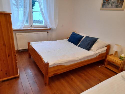 a bedroom with a bed with white sheets and blue pillows at Apartament Jeziorowy in Rydzewo